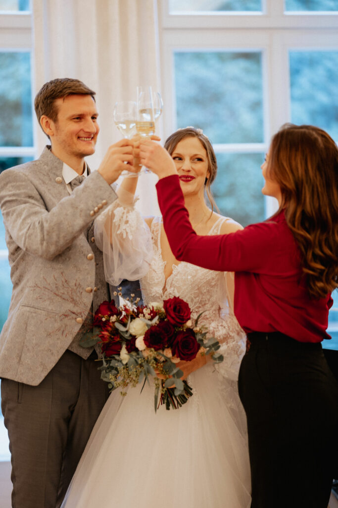 Brautpaar mit Hochzeitsplanerin beim Anstoßen